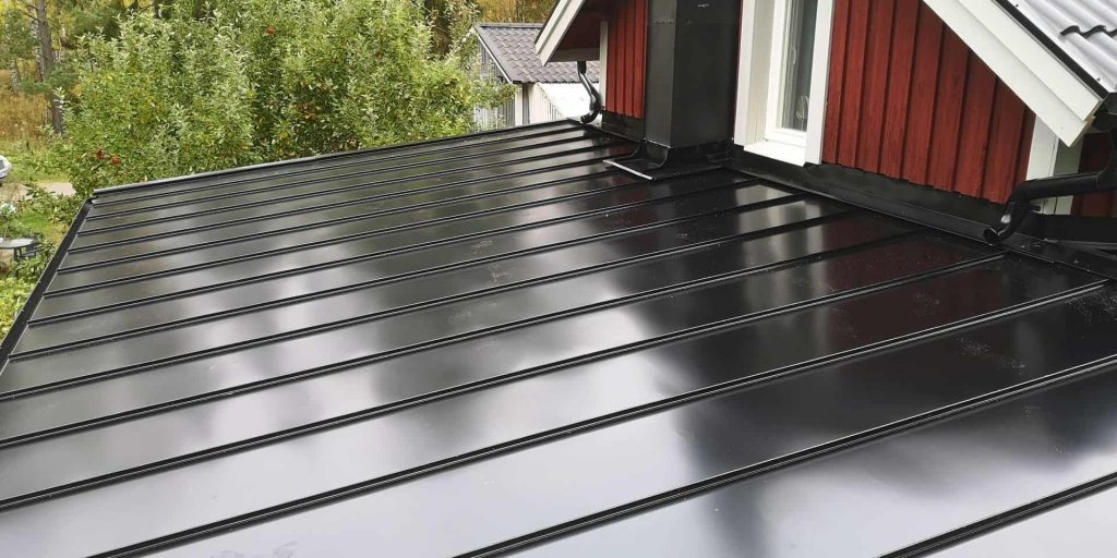 Nylagt svart falsat plåttak på ett rött trähus