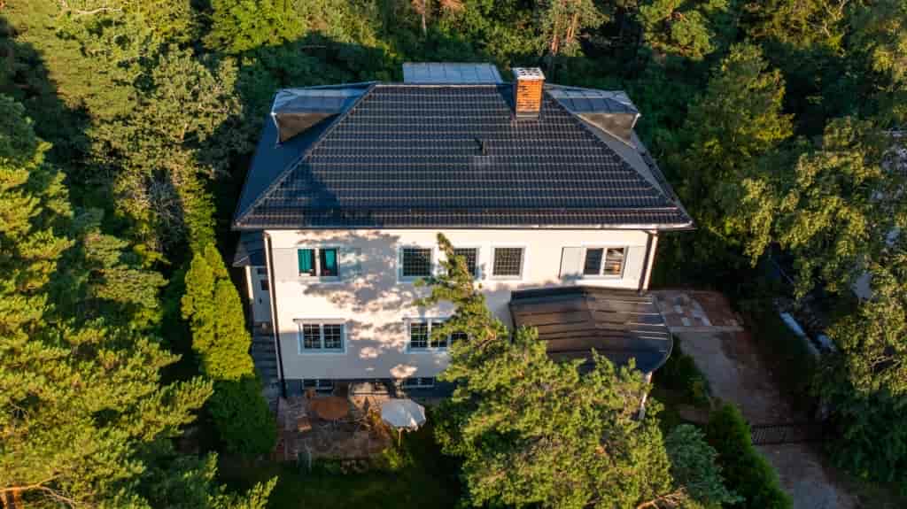 Flygbild över vit villa med nylagt svart tak