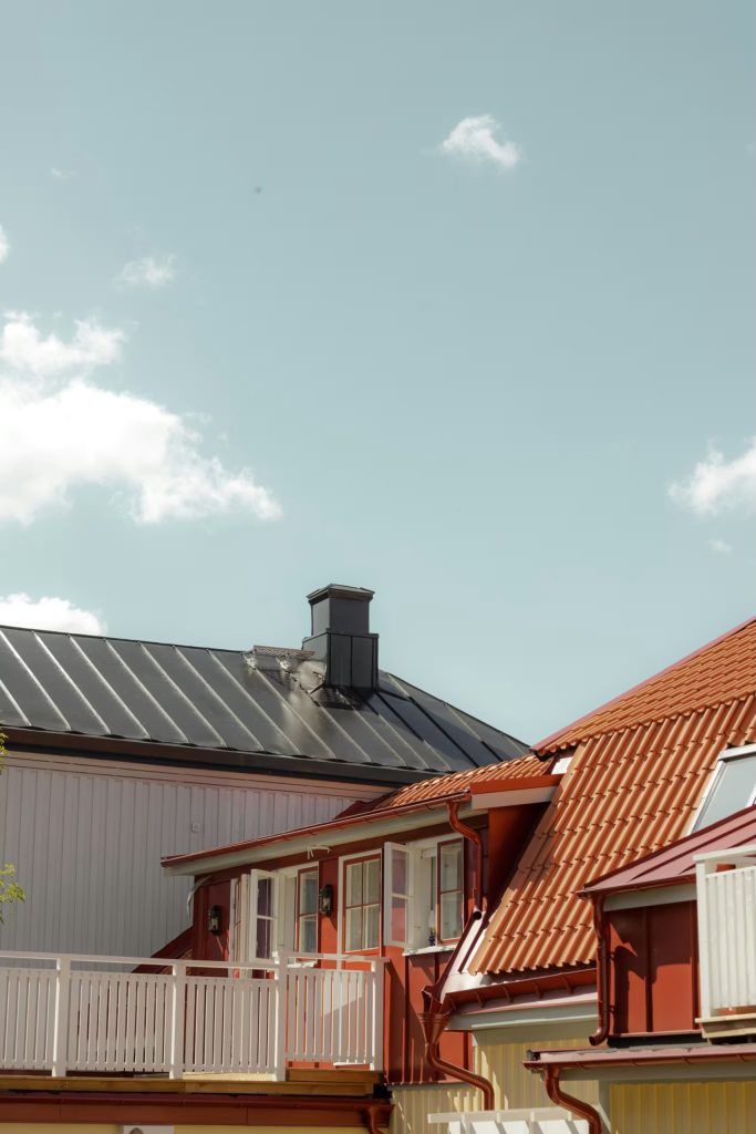 Rött tegeltak och svart plåttak mot blå himmel
