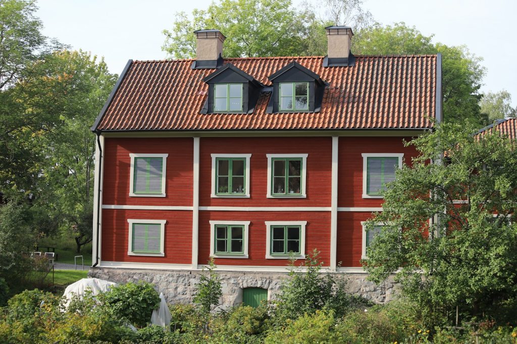 Rött trähus med tak av röda tegelpannor och takkupor på Långholmen i Stockholm